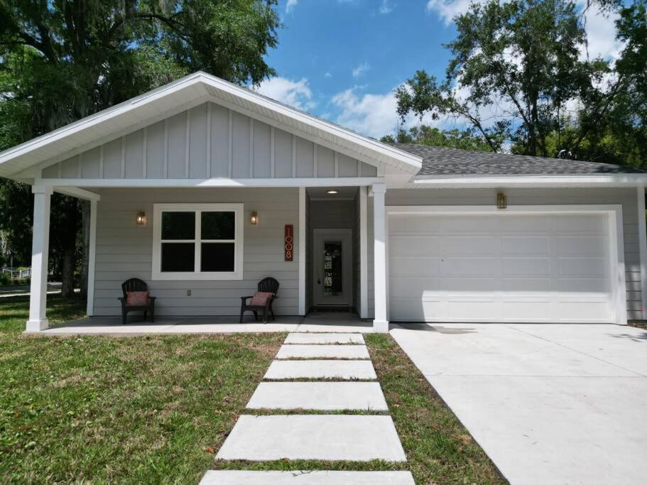 una casa blanca con dos sillas delante en Stylish House 2 miles from UF, en Gainesville