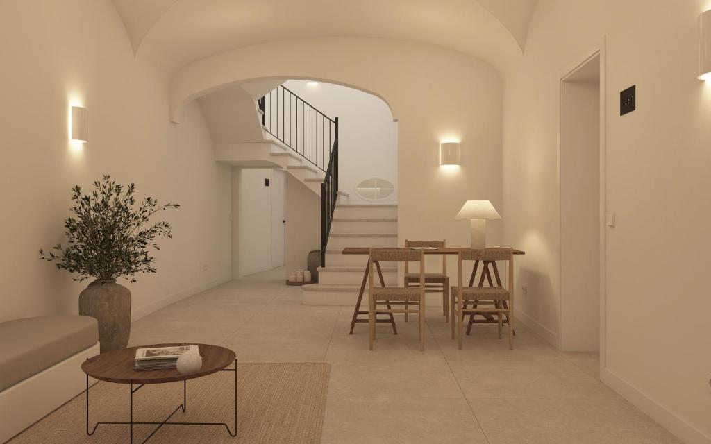 een woonkamer met een tafel en stoelen en een trap bij Tres Tocs in Ciutadella