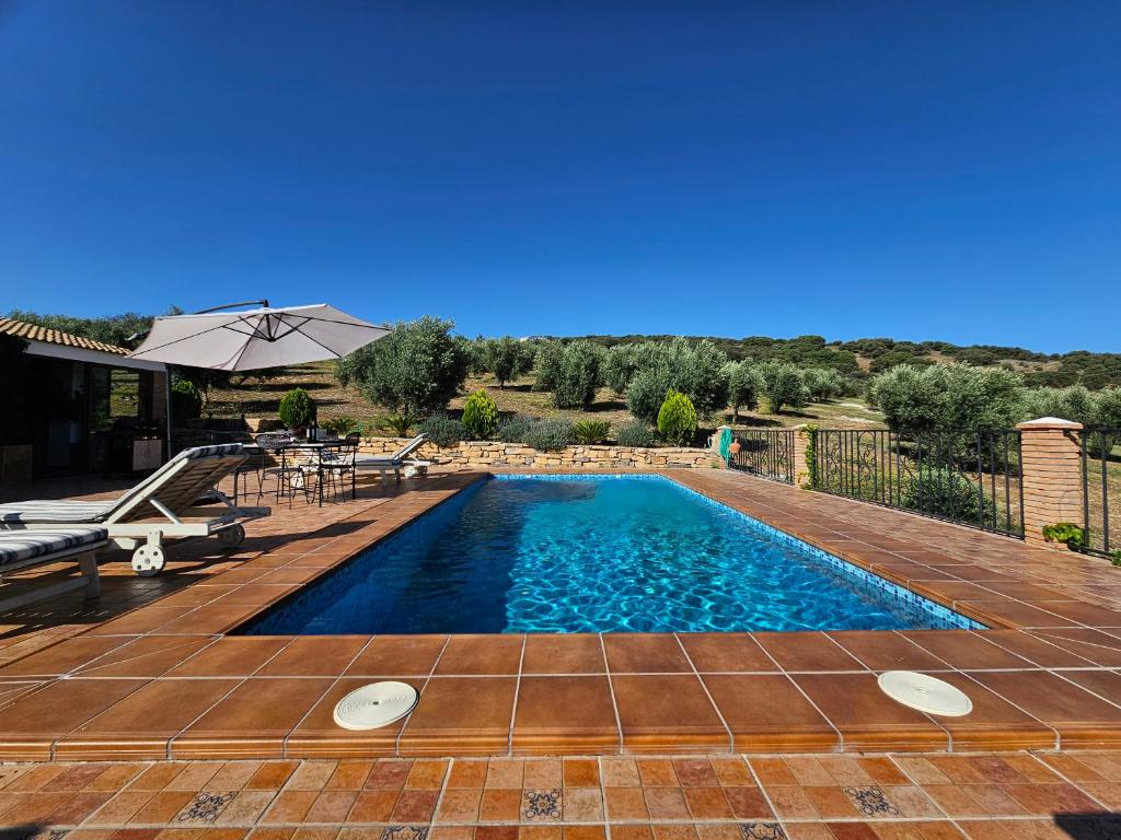 a swimming pool with a table and an umbrella at Villa San Nicolas - private, tranquil, relaxing.. in Ermita Nueva