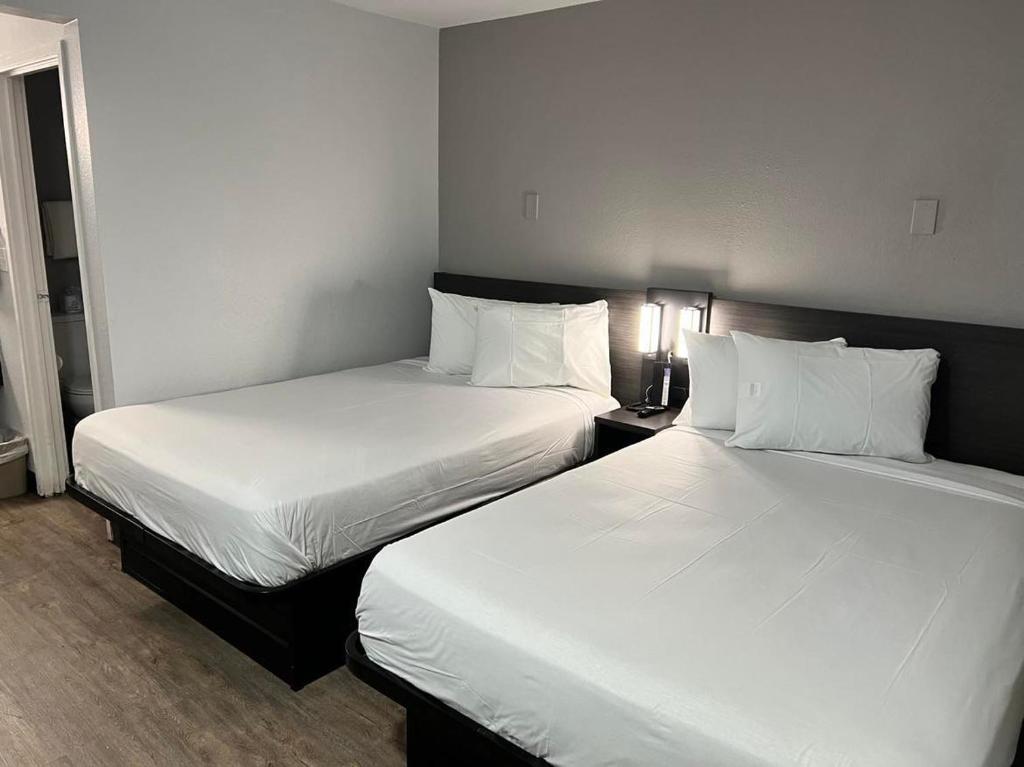 duas camas num quarto de hotel com lençóis brancos em Motel 6-Lakeland, FL em Lakeland