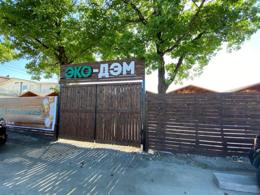 a wooden gate with a sign on it next to a fence at Коттеджи Эко-Дэм in Sukhum