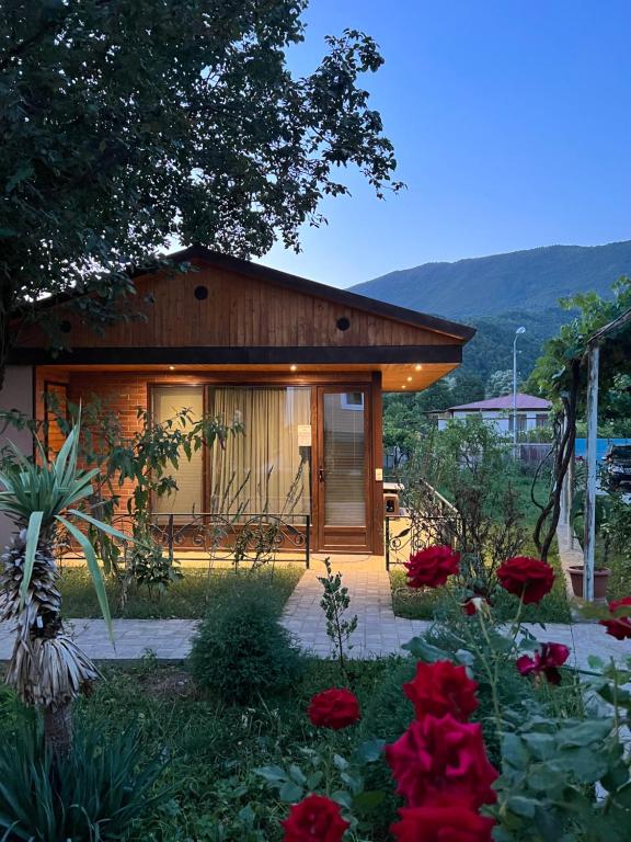 una casa con un jardín con flores rojas en Qoqosa In Racha en Ambrolauri