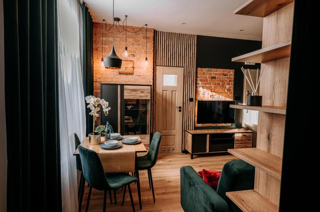 een eetkamer met een tafel en groene stoelen bij Apartament Mazury Kętrzyn „Kopernik” in Kętrzyn