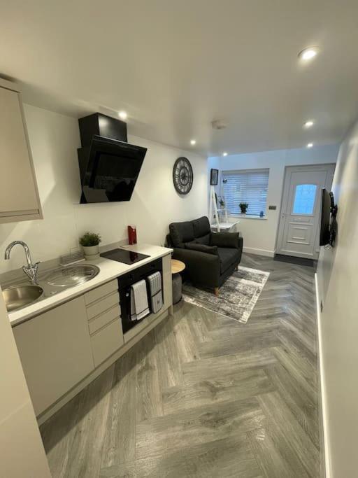 a kitchen with a sink and a living room at Stylish & Cosy 1 Bed Apartment in Swindon