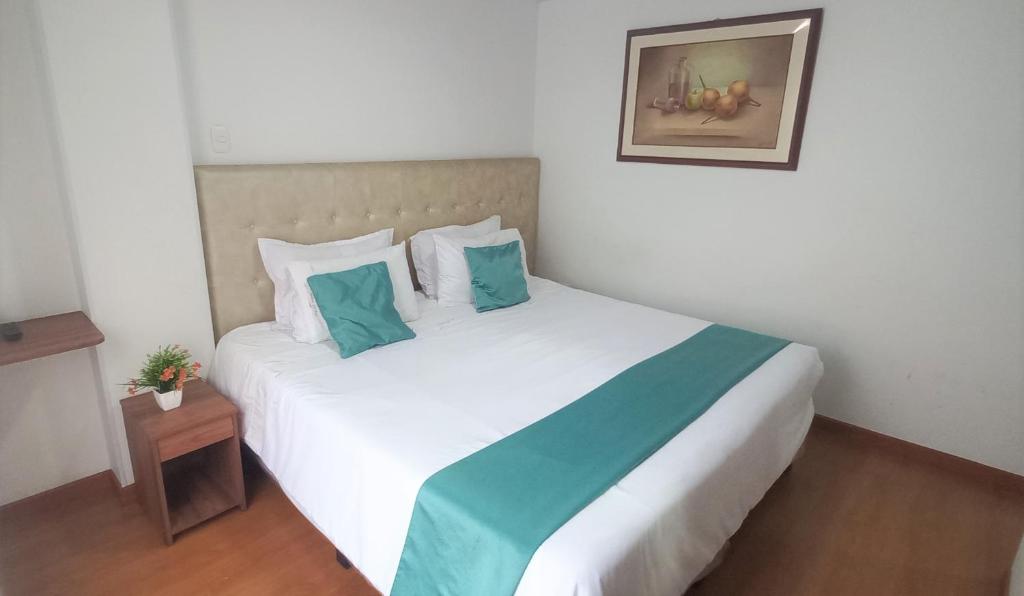 een slaapkamer met een groot wit bed met blauwe kussens bij Hotel en Bogota - Fontana Di Trevi in Bogota