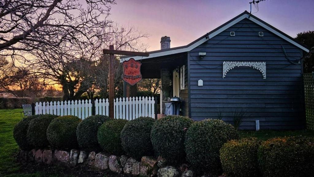 a blue house with a white fence and bushes at Peg Cottage in Evandale