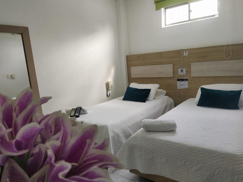 two beds in a room with a purple flower on the floor at Hotel La Casa 1 in Montería