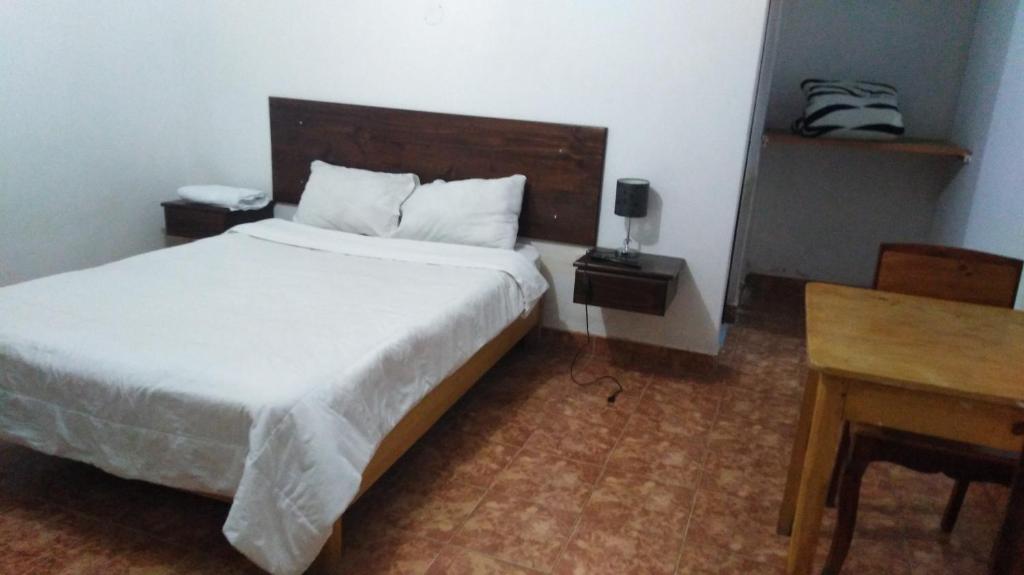 1 dormitorio con cama blanca y mesa de madera en La Farola Cajamarca, en Cajamarca