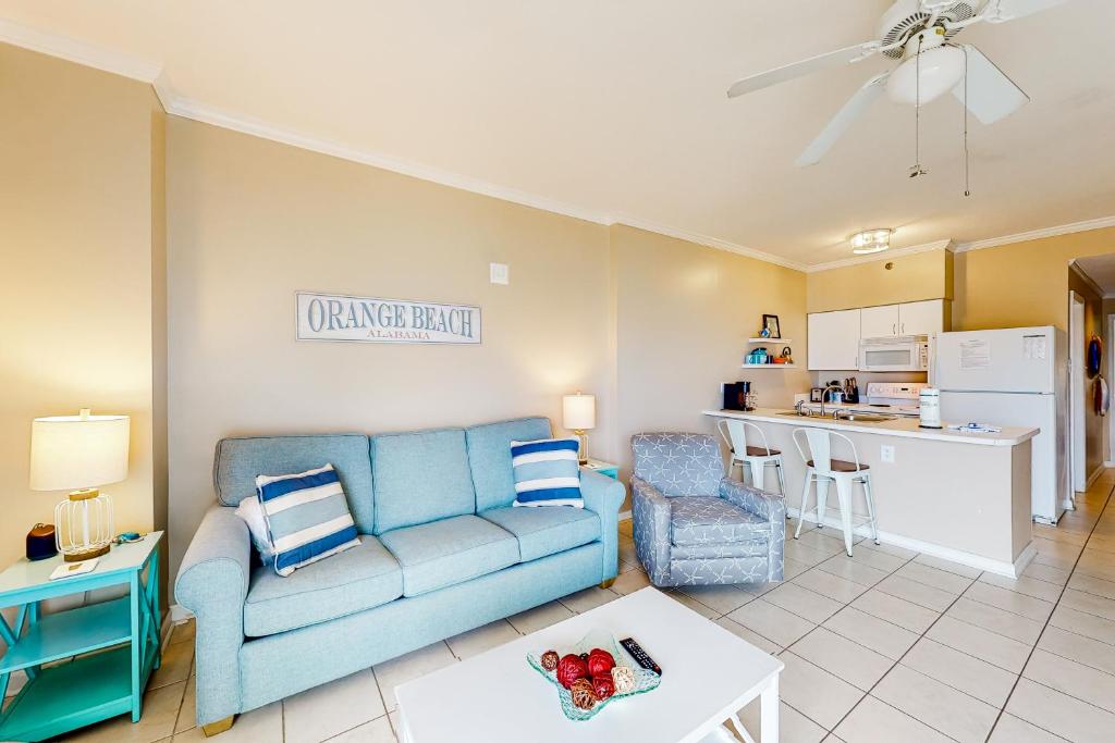 a living room with a blue couch and a kitchen at Tradewinds #1208 in Orange Beach