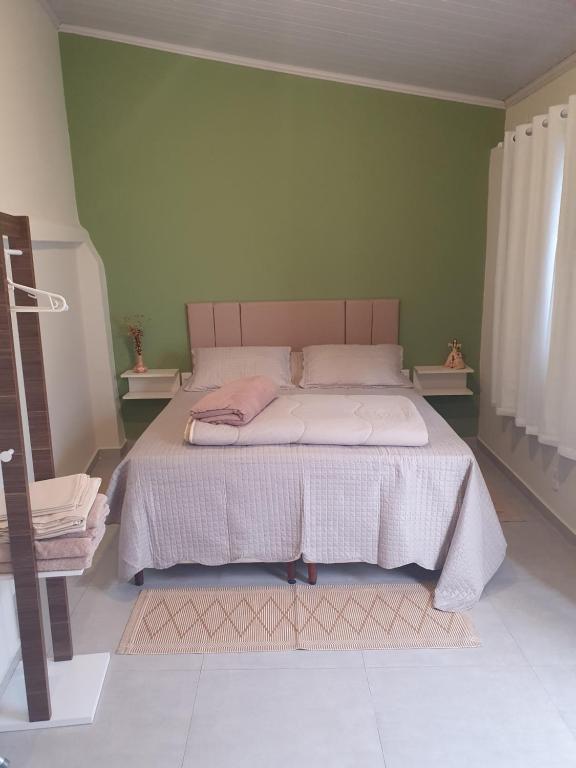 Suíte privativa confortável في ديامانتينا: سرير في غرفة نوم مع جدار أخضر