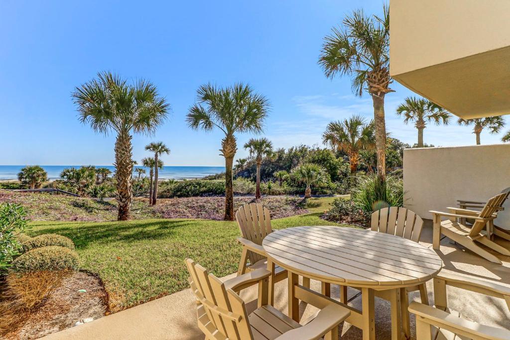 a patio with a table and chairs and palm trees at Captains Court 1019 in Fernandina Beach