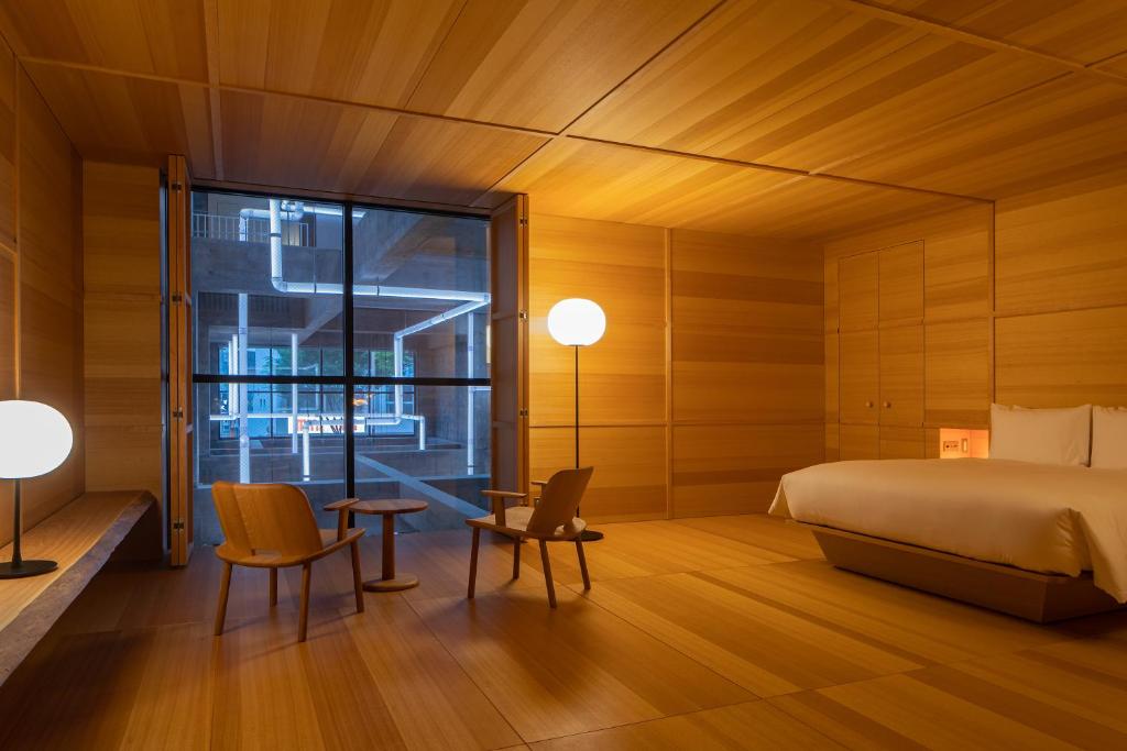 a bedroom with a bed and chairs and a window at SHIROIYA HOTEL in Maebashi