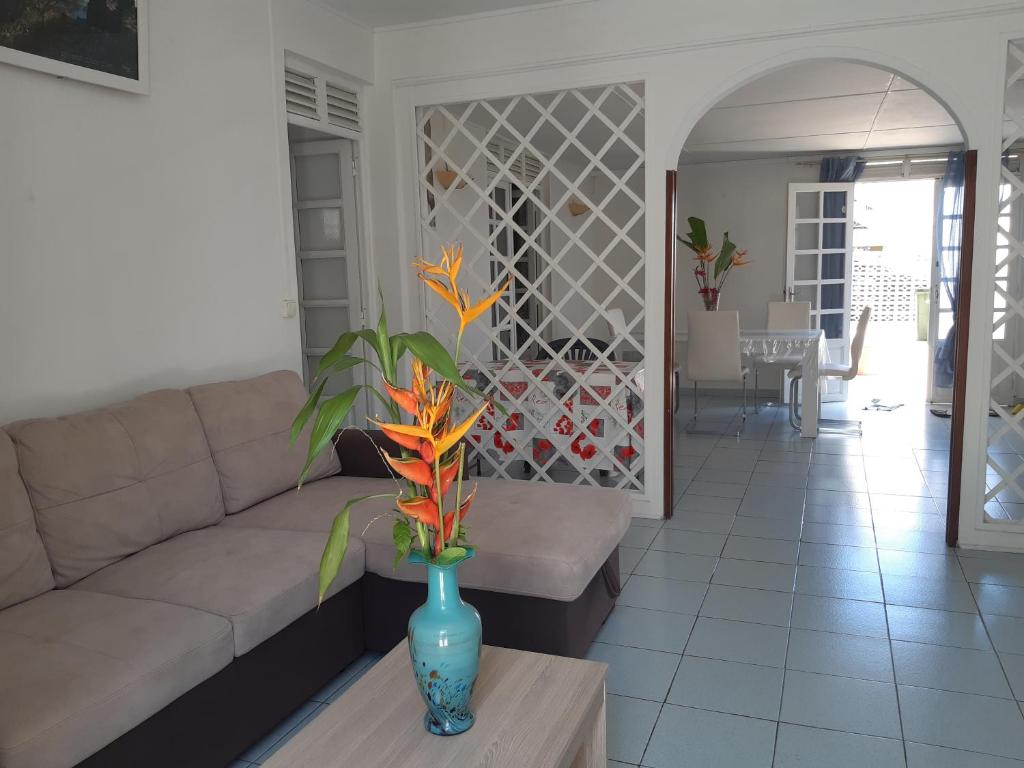 sala de estar con sofá y jarrón sobre una mesa en Les ptits flamboyants en Basse-Terre