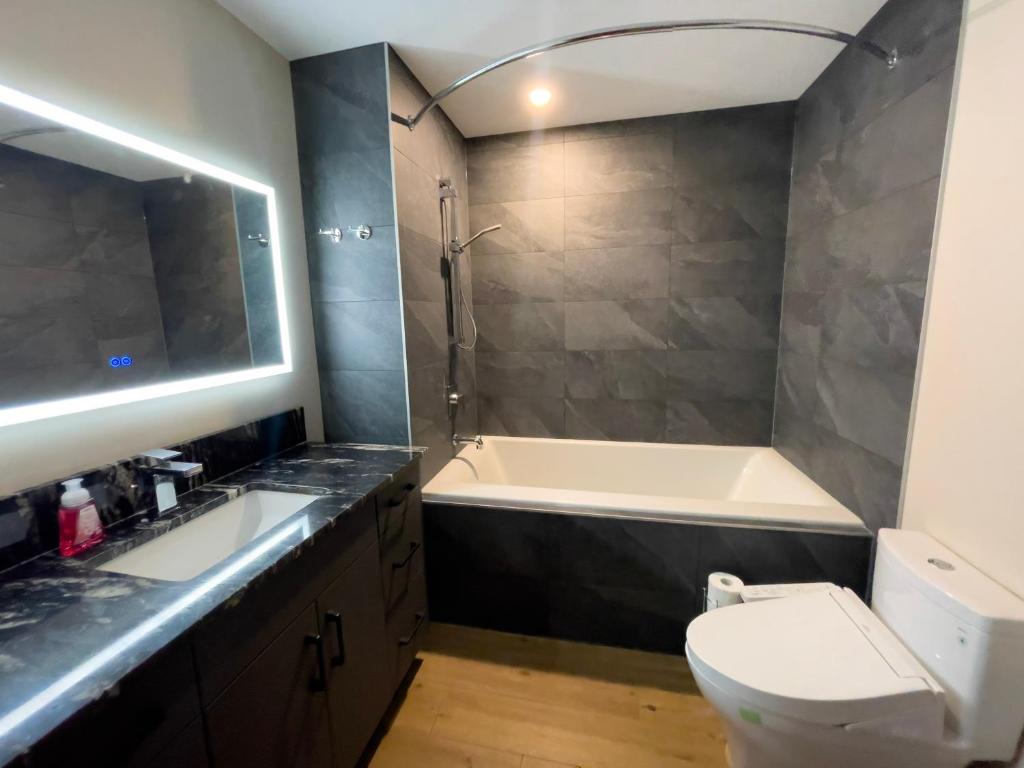 a bathroom with a tub and a toilet and a sink at Romantic Luxury Retreat with Private Sauna & Spa, Pet Friendly, Elkside Hideout B&B in Canmore