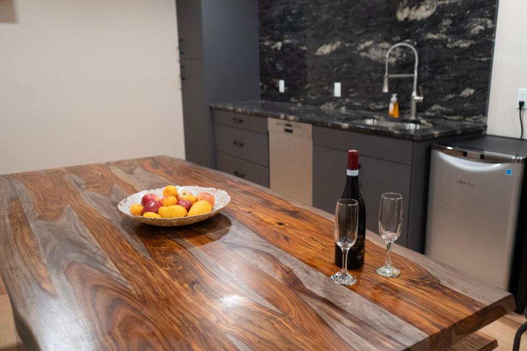 a wooden table with a bowl of fruit and a bottle of wine at Romantic Luxury Retreat with Private Sauna & Spa, Pet Friendly, Elkside Hideout B&B in Canmore