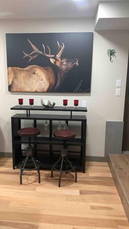 a painting of a deer on a wall with two bar stools at Romantic Luxury Retreat with Private Sauna & Spa, Pet Friendly, Elkside Hideout B&B in Canmore