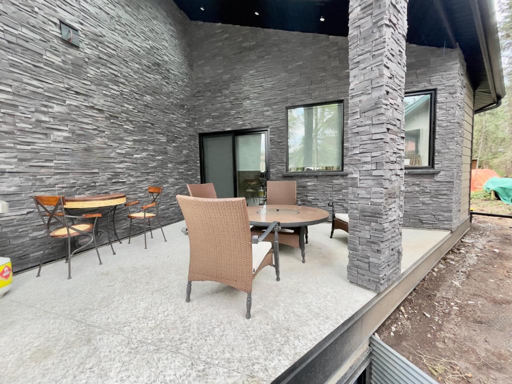 a patio with a table and chairs and a brick wall at Romantic Luxury Retreat with Private Sauna & Spa, Pet Friendly, Elkside Hideout B&B in Canmore