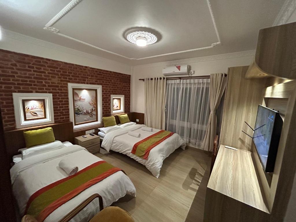a hotel room with two beds and a tv at Raniban Suites - Studio Apartment in Kathmandu