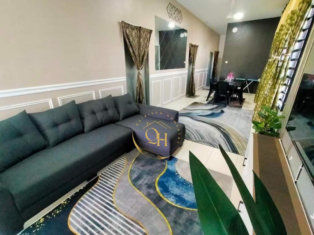 ein Wohnzimmer mit einem blauen Sofa und einem Teppich in der Unterkunft Qairissa Homestay Kuantan in Kuantan