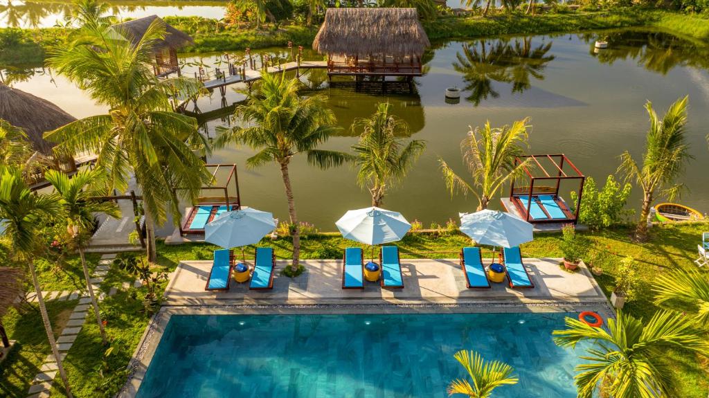 an aerial view of a resort pool with umbrellas and chairs at ZEN RETREAT HOI AN in Hoi An