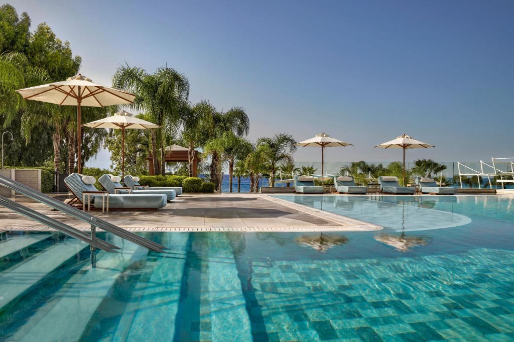 a large swimming pool with chairs and umbrellas at Parklane, a Luxury Collection Resort & Spa, Limassol in Limassol