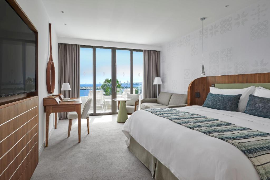 a hotel room with a large bed and a desk at Parklane, a Luxury Collection Resort & Spa, Limassol in Limassol