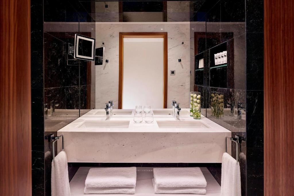 a bathroom with a large white tub with a mirror at Parklane, a Luxury Collection Resort & Spa, Limassol in Limassol