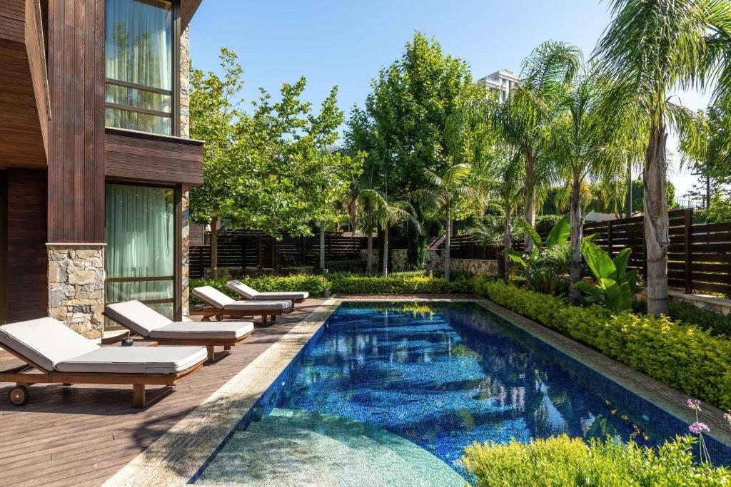 a swimming pool with lounge chairs and a house at Parklane, a Luxury Collection Resort & Spa, Limassol in Limassol