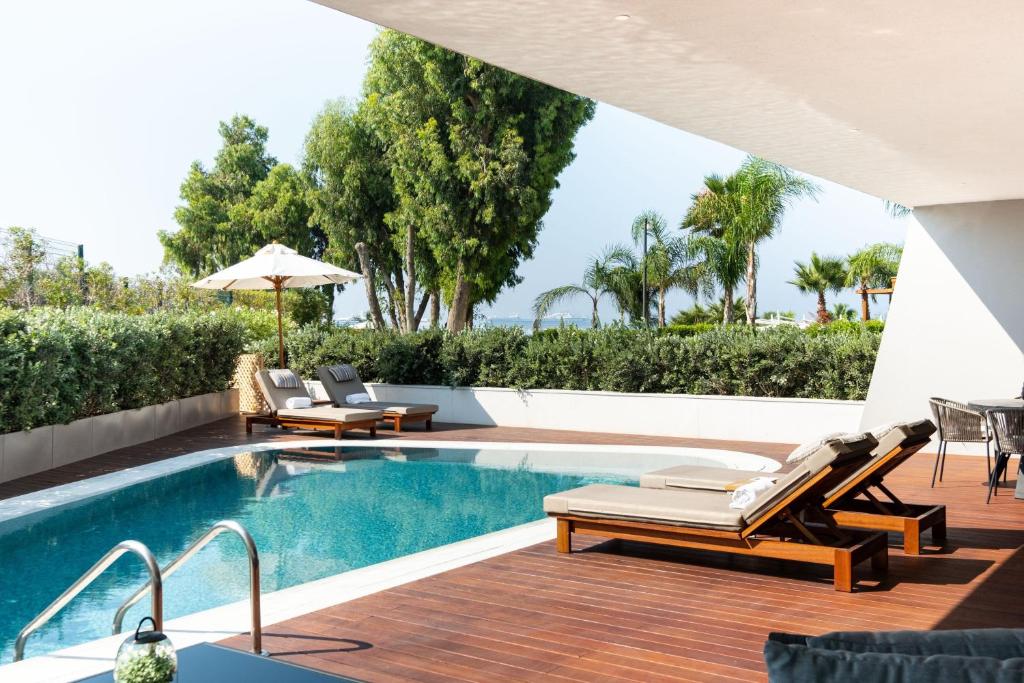 a pool with chaise lounge chairs next to a swimming pool at Parklane, a Luxury Collection Resort & Spa, Limassol in Limassol