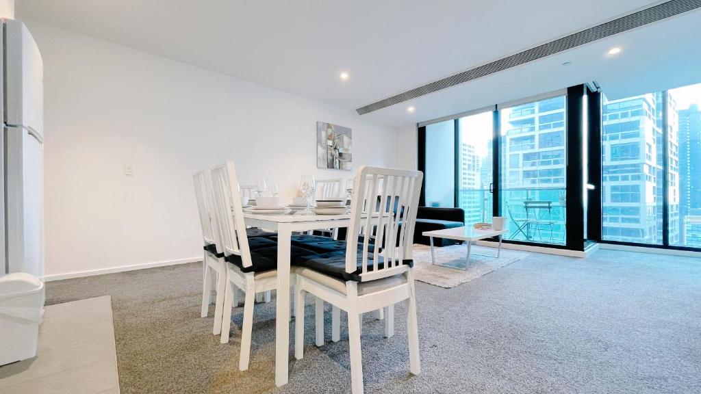 メルボルンにあるMelbourne One 2B2B1C Apartment by GoodLiveの白いダイニングルーム(テーブル、椅子付)