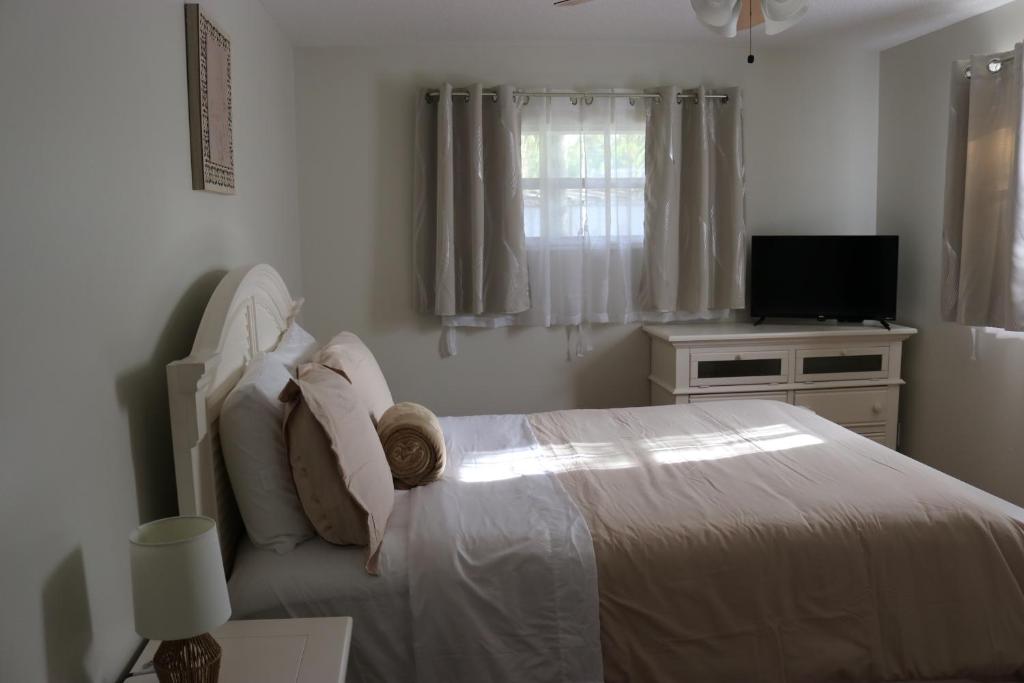 a white bedroom with a bed and a television at Hidden Emerald-Apartment with Kitchen and Laundry in Lakeland