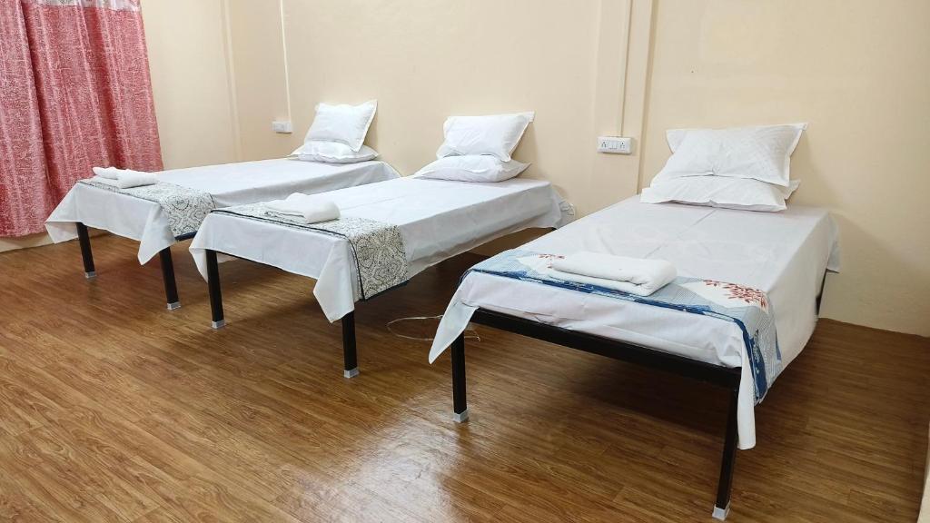 two twin beds in a hospital room with wooden floors at Nain Guest House in Ujjain