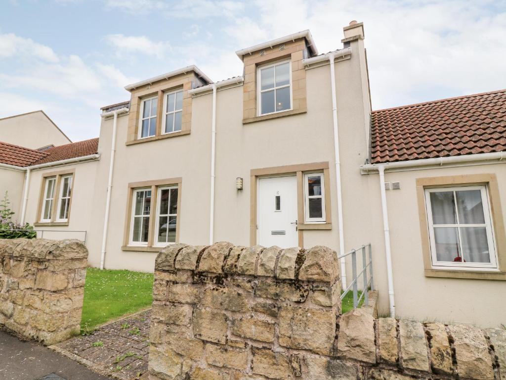 una casa con una pared de piedra delante de ella en Glebe Cottage Number 6 en St Andrews