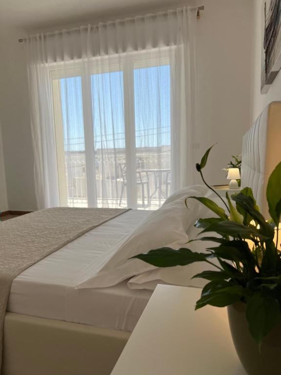 a white bedroom with a bed and a large window at Domusvacanza Salento in Santa Caterina di Nardò