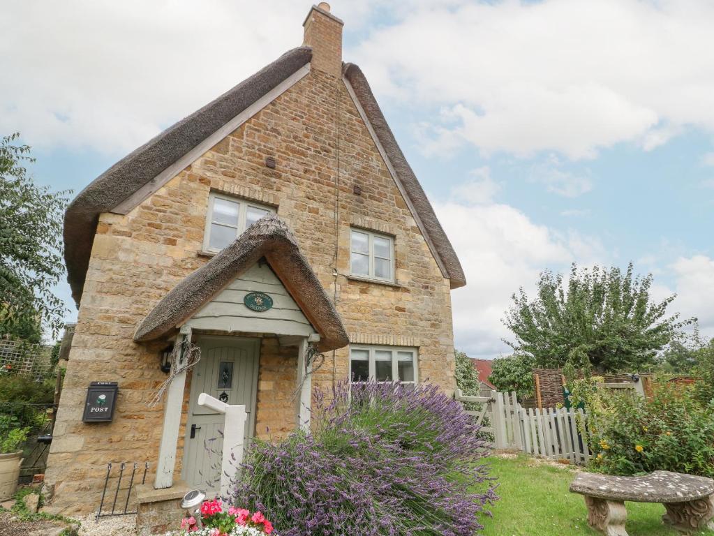 a small brick house with a thatched roof at Honeysuckle Cottage Brailes in Sutton under Brailes