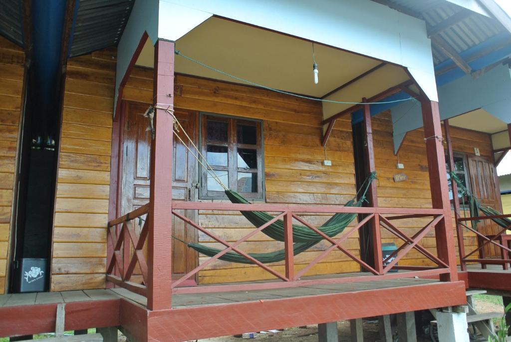 a front porch of a wooden house with a swing at Tavendang Guesthouse in Don Det