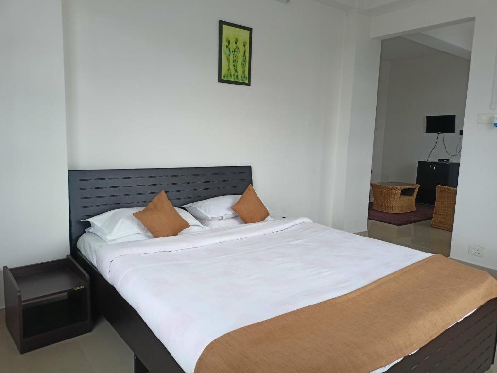1 dormitorio con 1 cama grande con sábanas blancas en Lashisha en Shillong