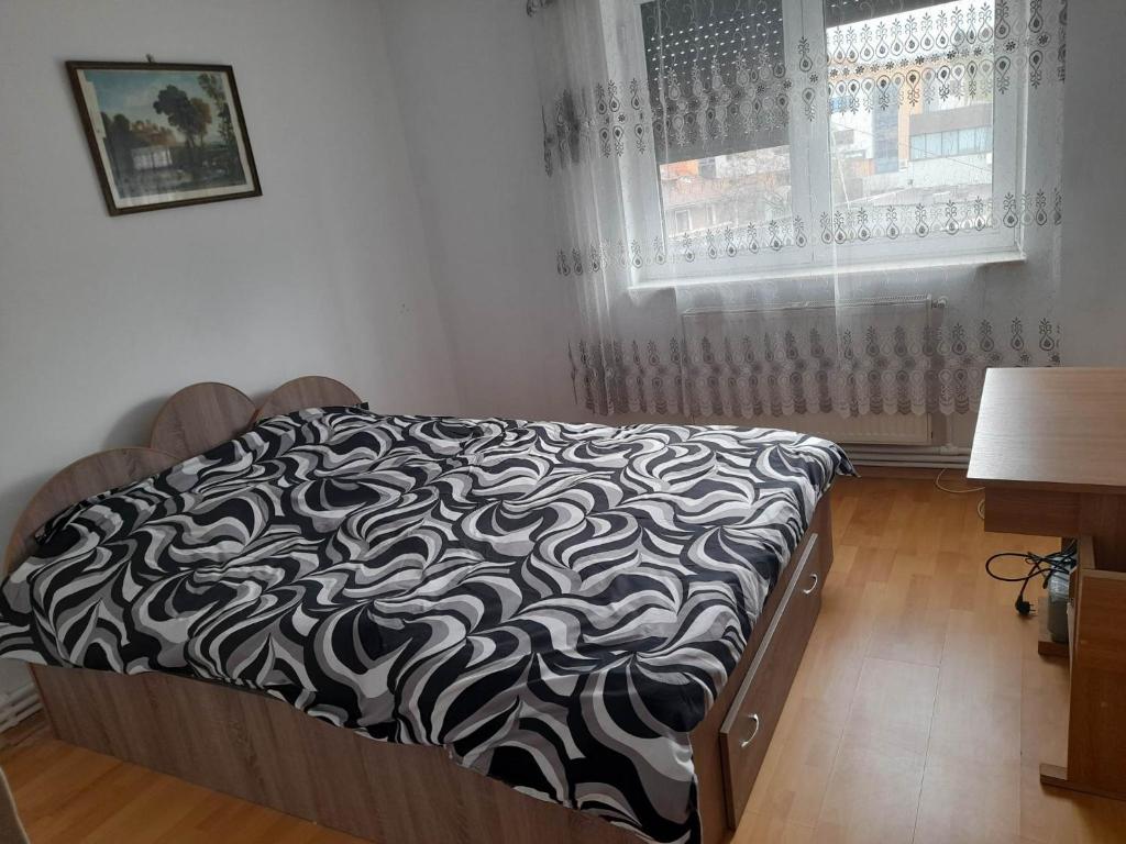 uma cama com um edredão preto e branco e uma janela em 4 rooms apartment downtown Pitesti em Piteşti