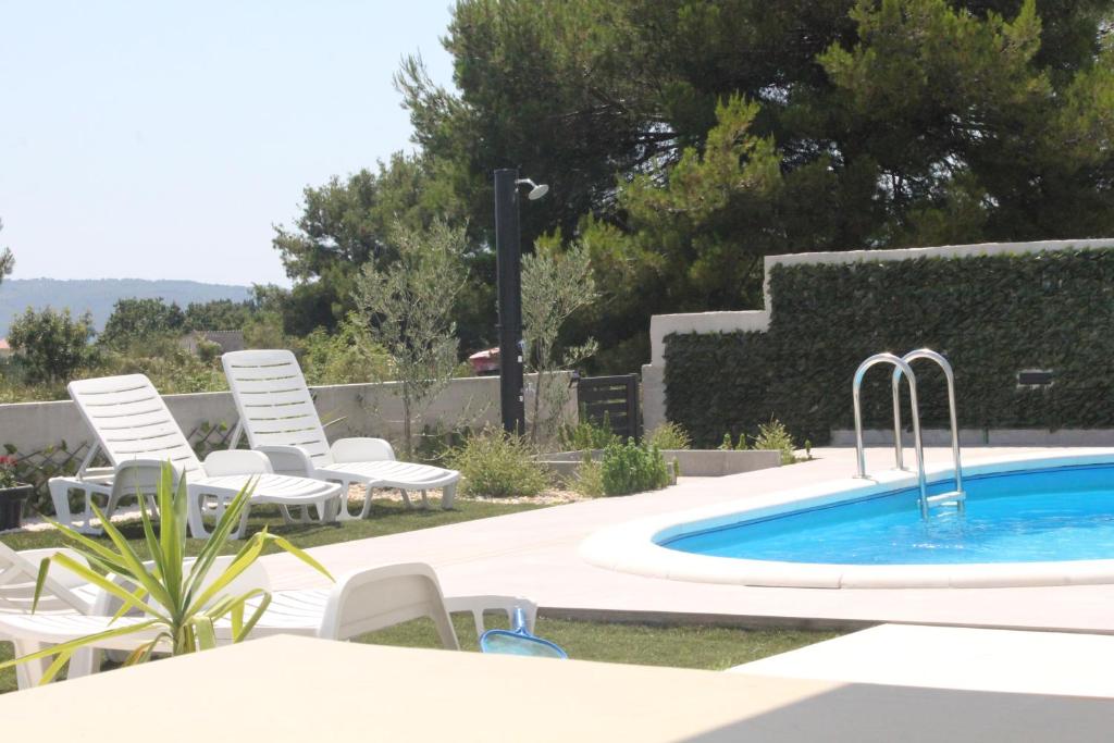 uma piscina com cadeiras brancas e uma piscina em Villa Marta 3 bedrooms, 2 baths and pool em Kaštel Štafilić