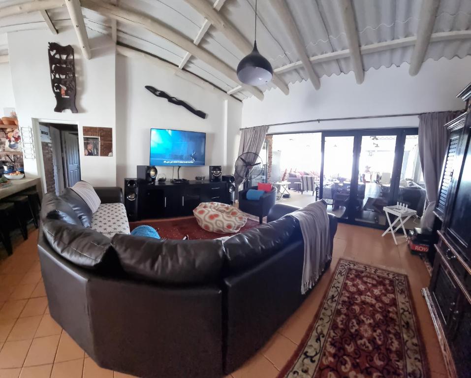 sala de estar con sofá de cuero y TV en Bazley la Paradis, en Bazley Beach