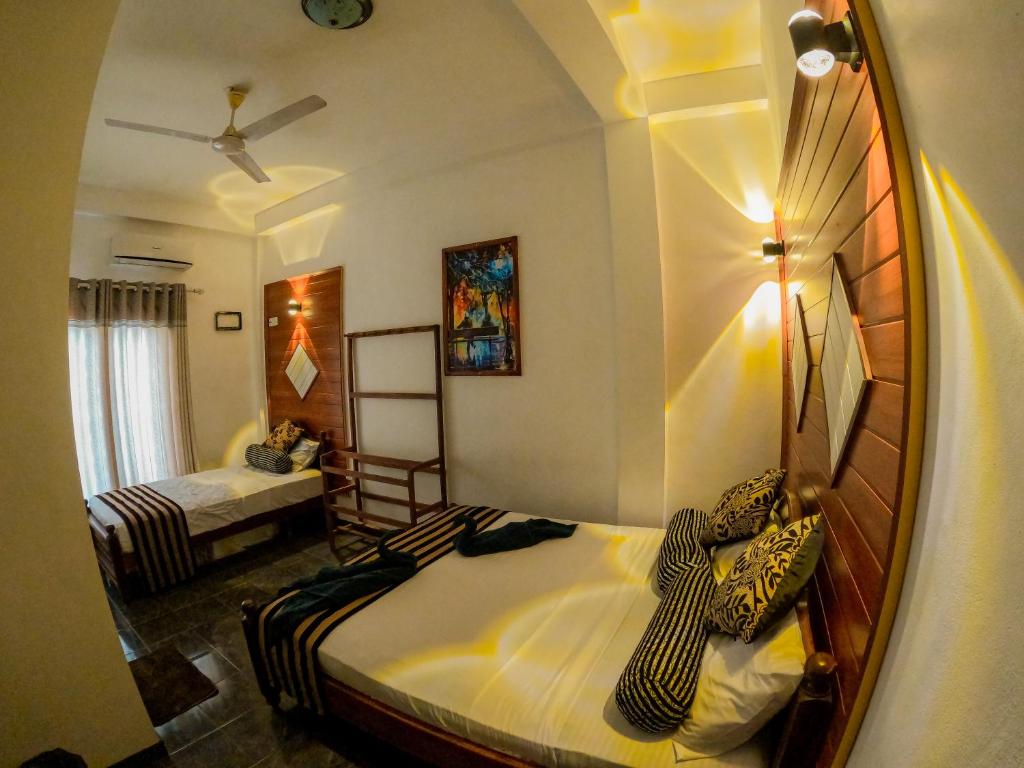 a bedroom with two beds and a mirror at Hotel Blackstone in Hambantota