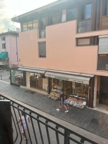 a person walking in front of a store on a street at Cavour Apartment Center Bardolino in Bardolino