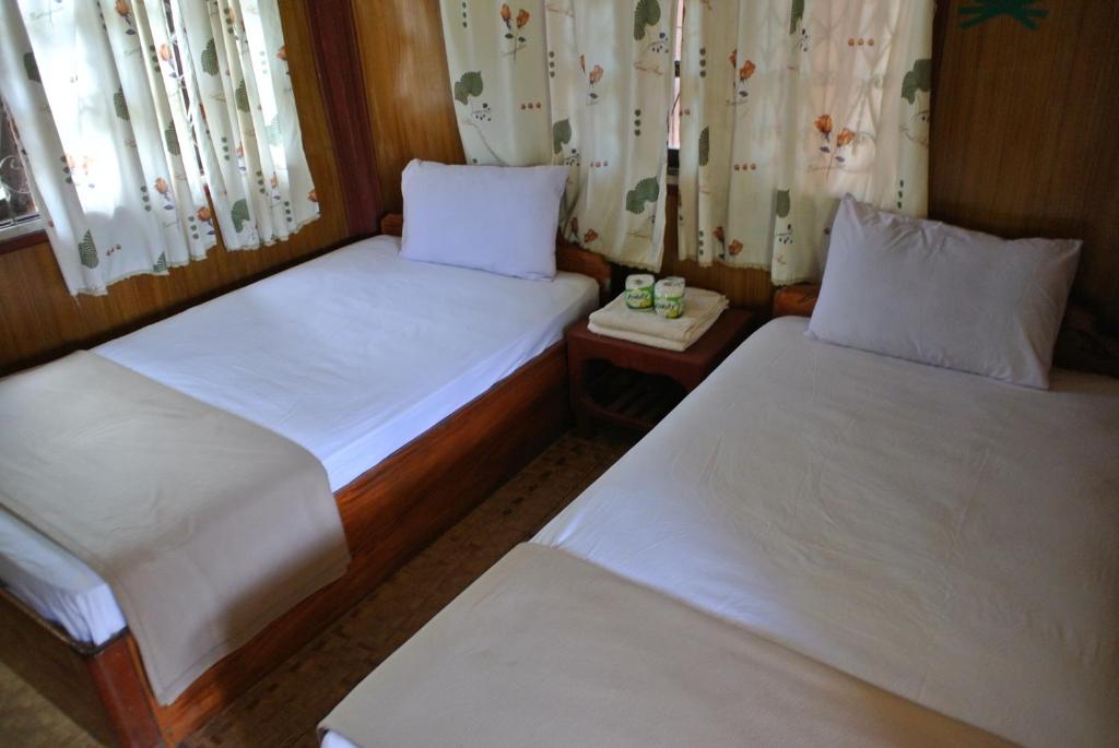 2 Betten in einem kleinen Zimmer mit Fenstern in der Unterkunft Dalom Guesthouse in Don Det