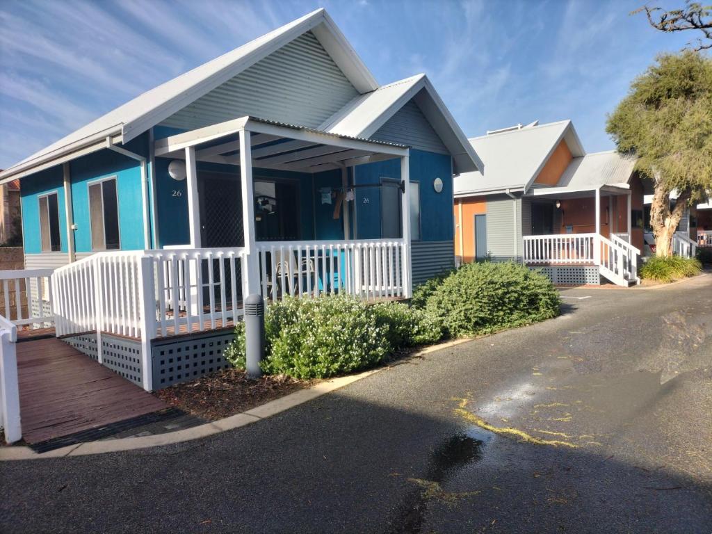 a blue house with a white fence on a street at Mandurah Ocean Marina Chalets in Mandurah