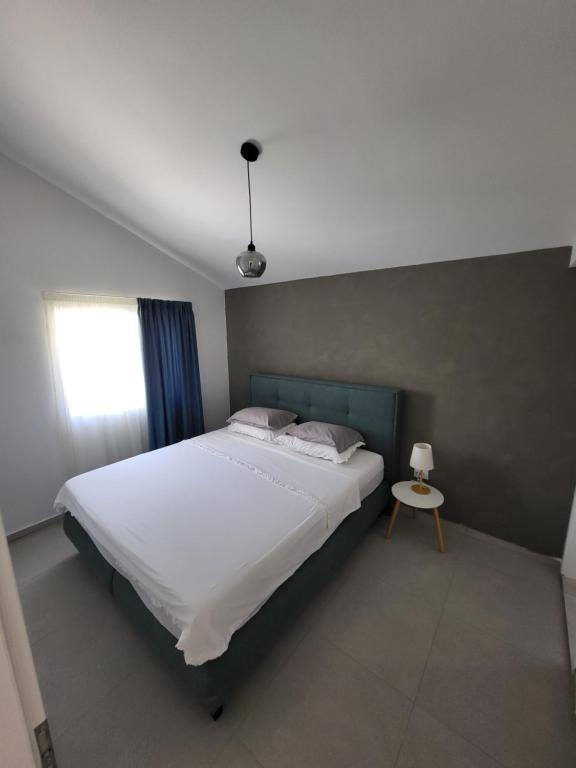 Un dormitorio con una gran cama blanca y una mesa en Apartmani J&I, en Pakoštane