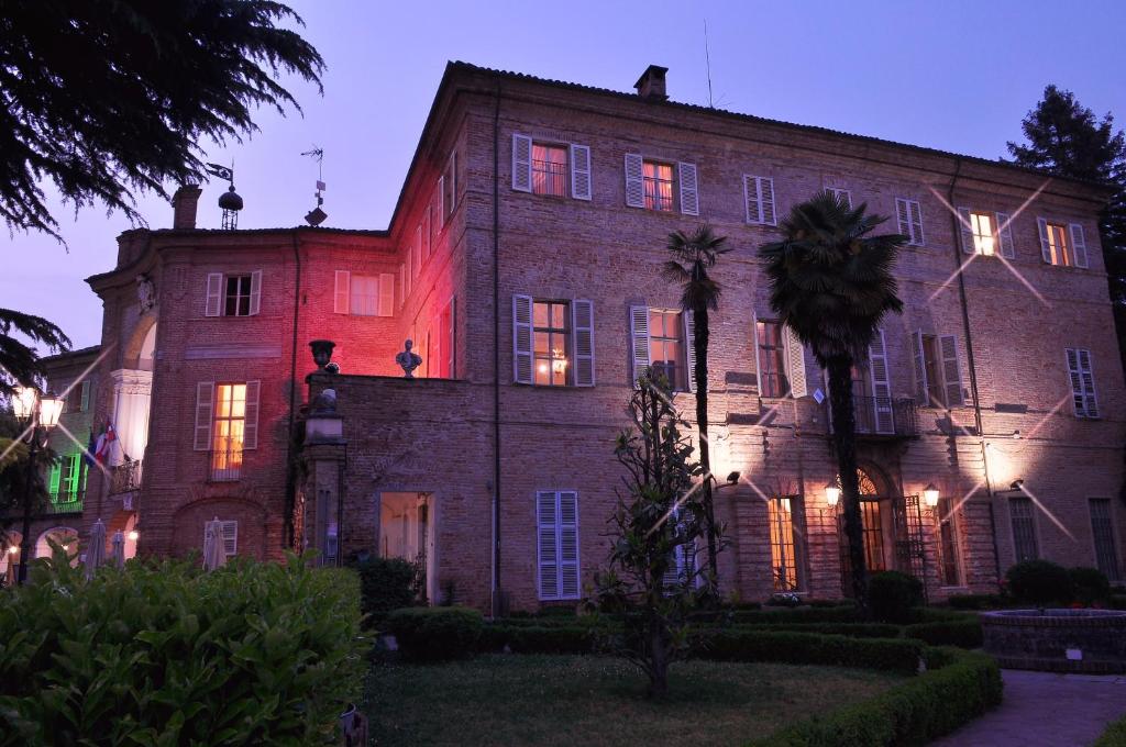 un grande edificio in mattoni con una luce rossa sopra di La Foresteria del Castello - Wellness Hotel in Dimora Storica a CastellʼAlfero