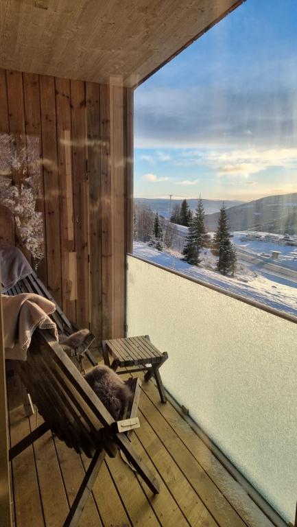 un fauteuil à bascule sur une terrasse avec une grande fenêtre dans l'établissement New and fresh apartement in Kvitfjell, à Favang