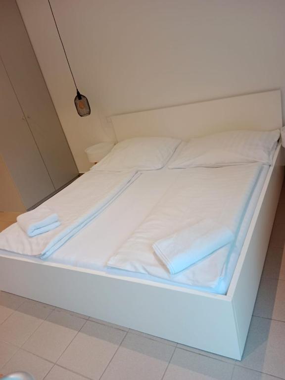 a white bed with two pillows on it at Storchencamp Gästehaus Purbach in Purbach am Neusiedlersee
