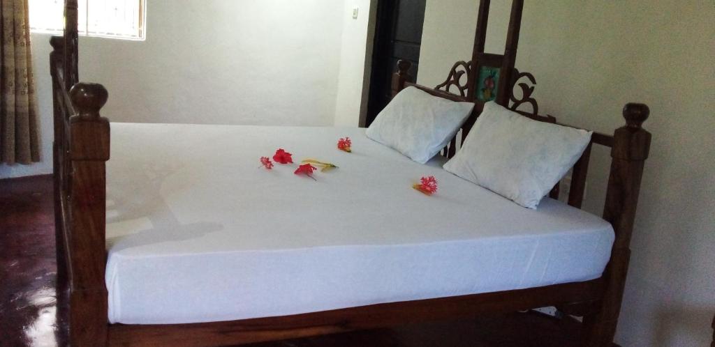a bed with white sheets and red flowers on it at The Dream Garden Bungalow in Kizimkazi