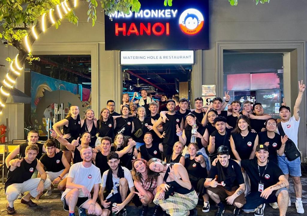 Un gruppo di persone che posano per una foto davanti a un negozio di Mad Monkey Hanoi a Hanoi